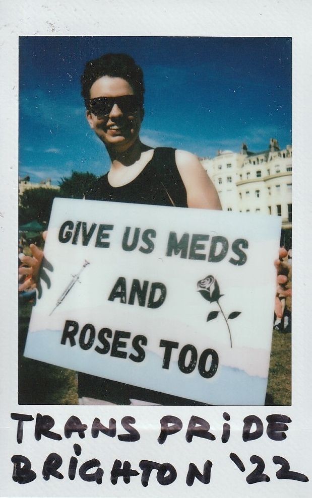 A person holding a sign reading, "Give us meds and roses too".