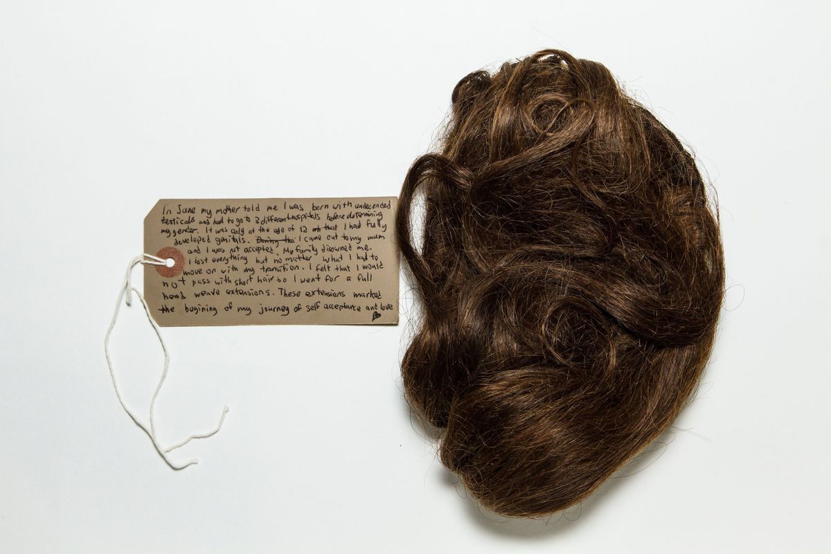 A handwritten note rests beside a bundle of brown hair.