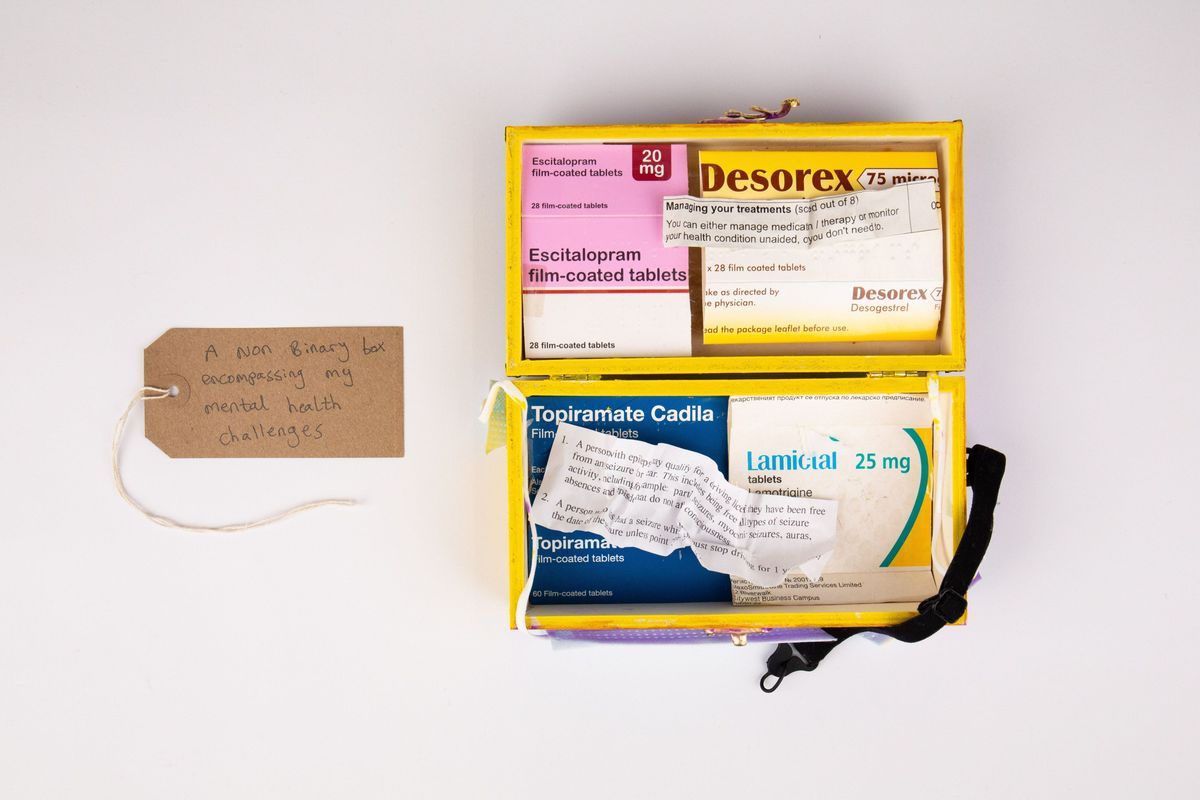 The image shows a yellow box containing medication boxes with a tag reading, "A non-binary box..."