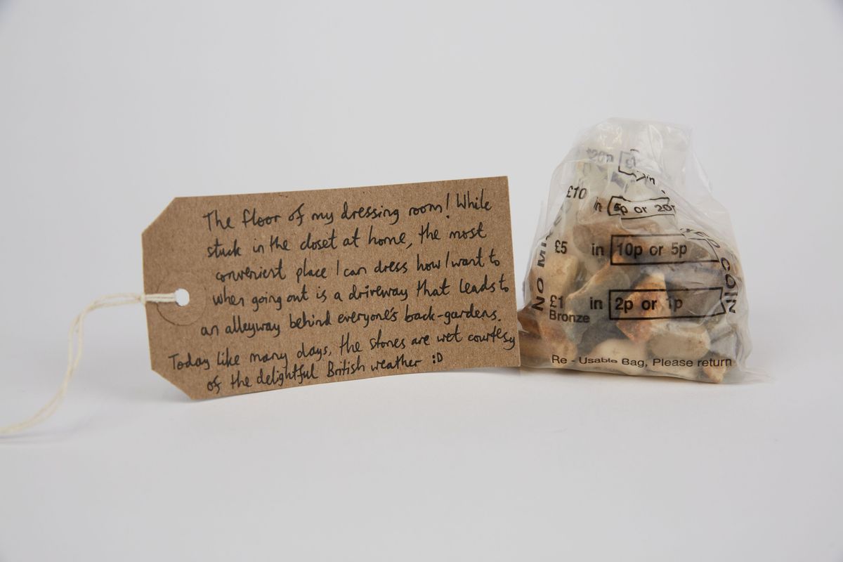 A plastic money bag filled with pebbles, with a brown handwritten luggage tag.