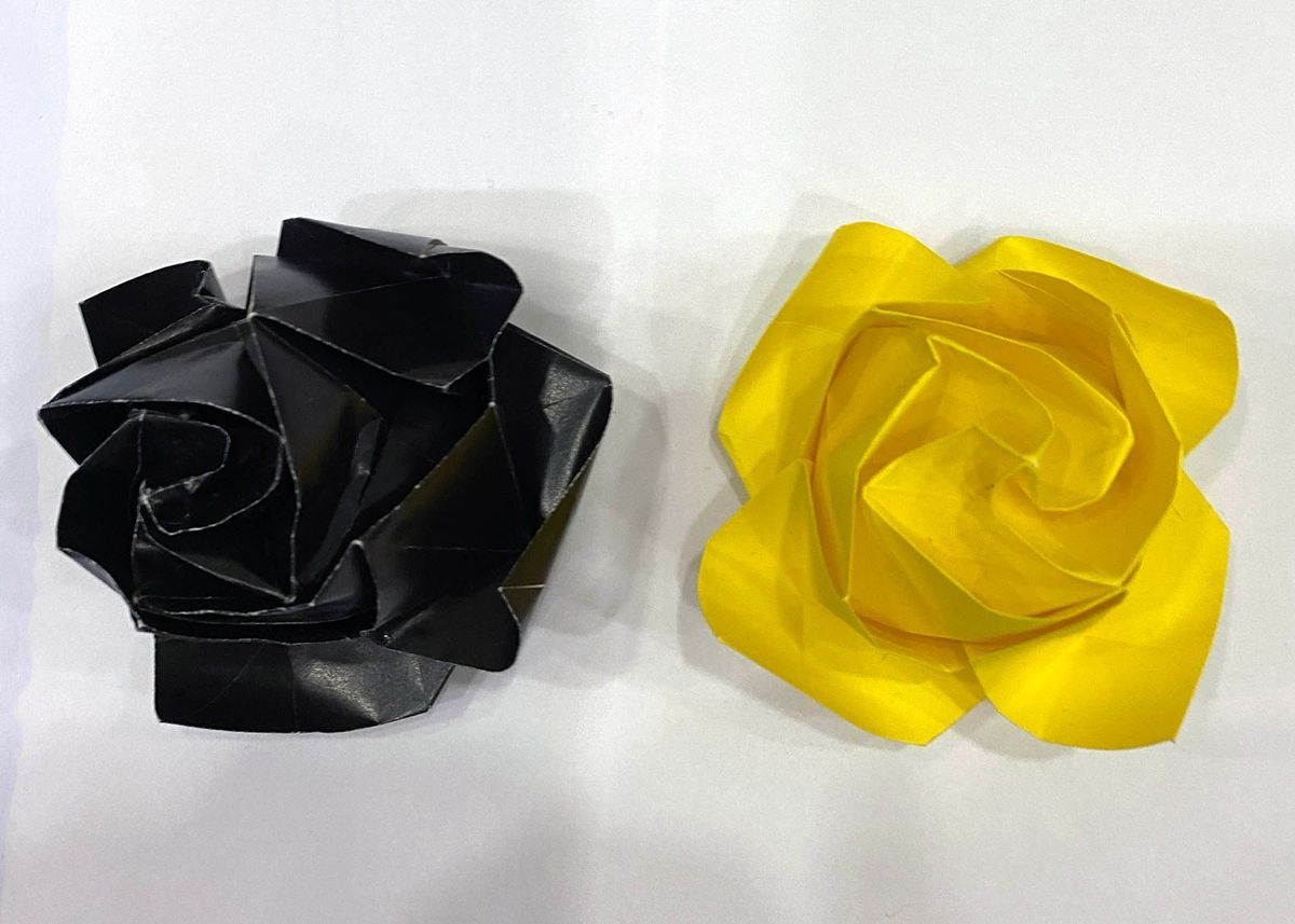 Two handmade origami roses. One black, one yellow.