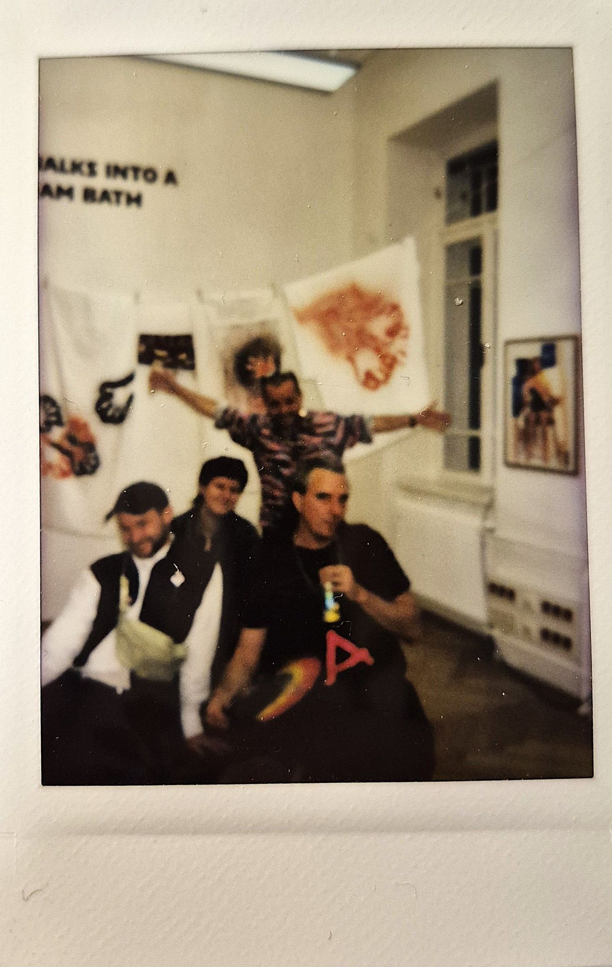 Four people are posing together in a room with artwork.