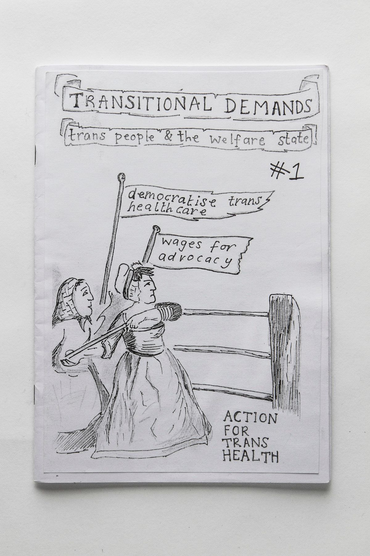 Two identical booklets "Transitional Demands #1 trans people & the welfare state". Both photocopies, 26 pages. Hand drawn front cover. Both in good condition though have been well read, both have black hanging wire.