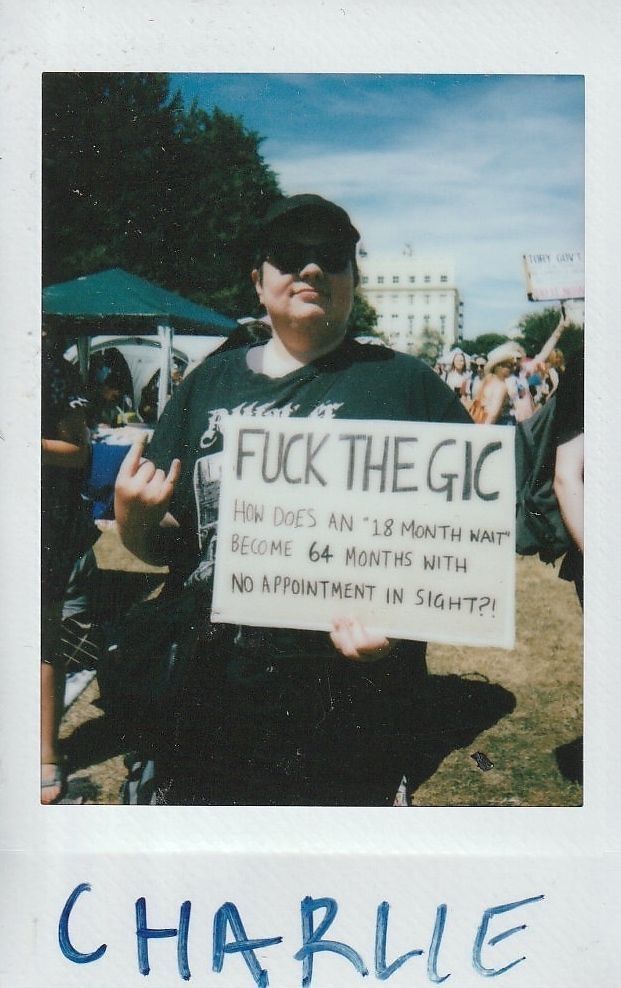 A person is holding a protest sign which says "Fuck The GIC".