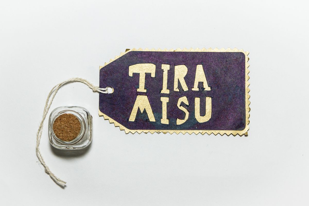 A glass jar with a cork in it next to a label which says TIRA MISU.