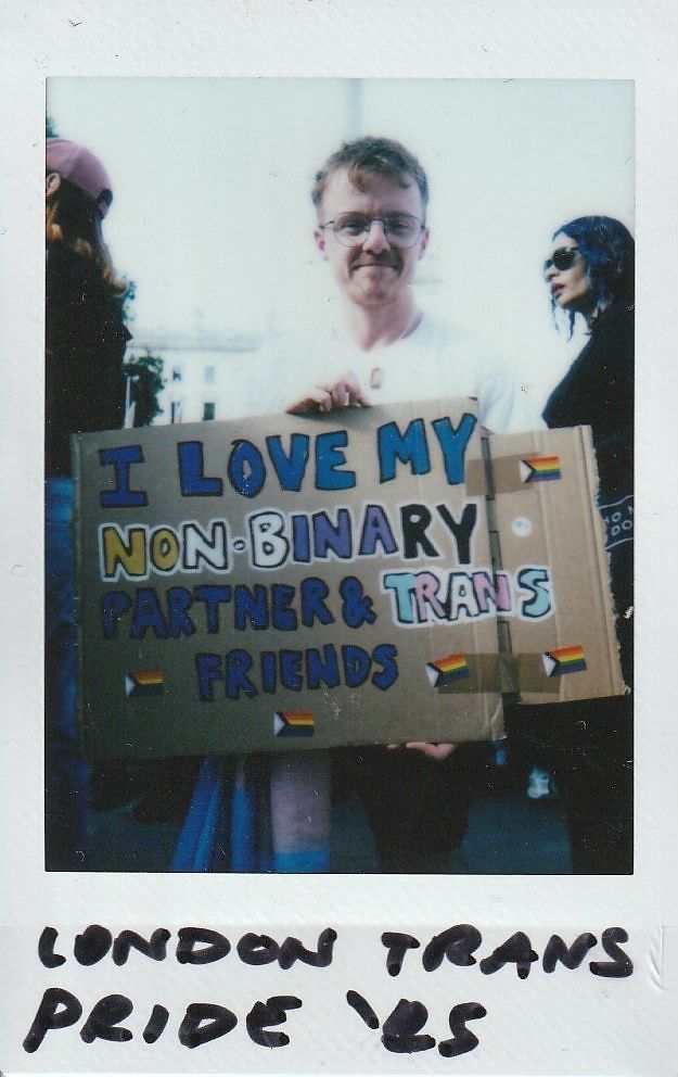 A person holds a placard which says "I Love My Non-Binary Partner & Trans Friends".
