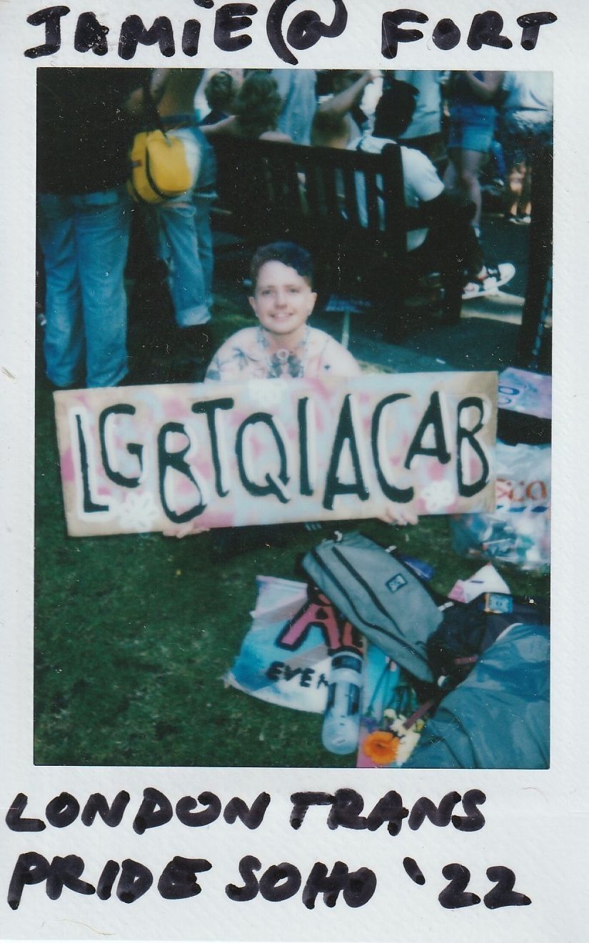 A person at London Trans Pride in Soho holds a colorful sign reading "LGBTQIACAB".