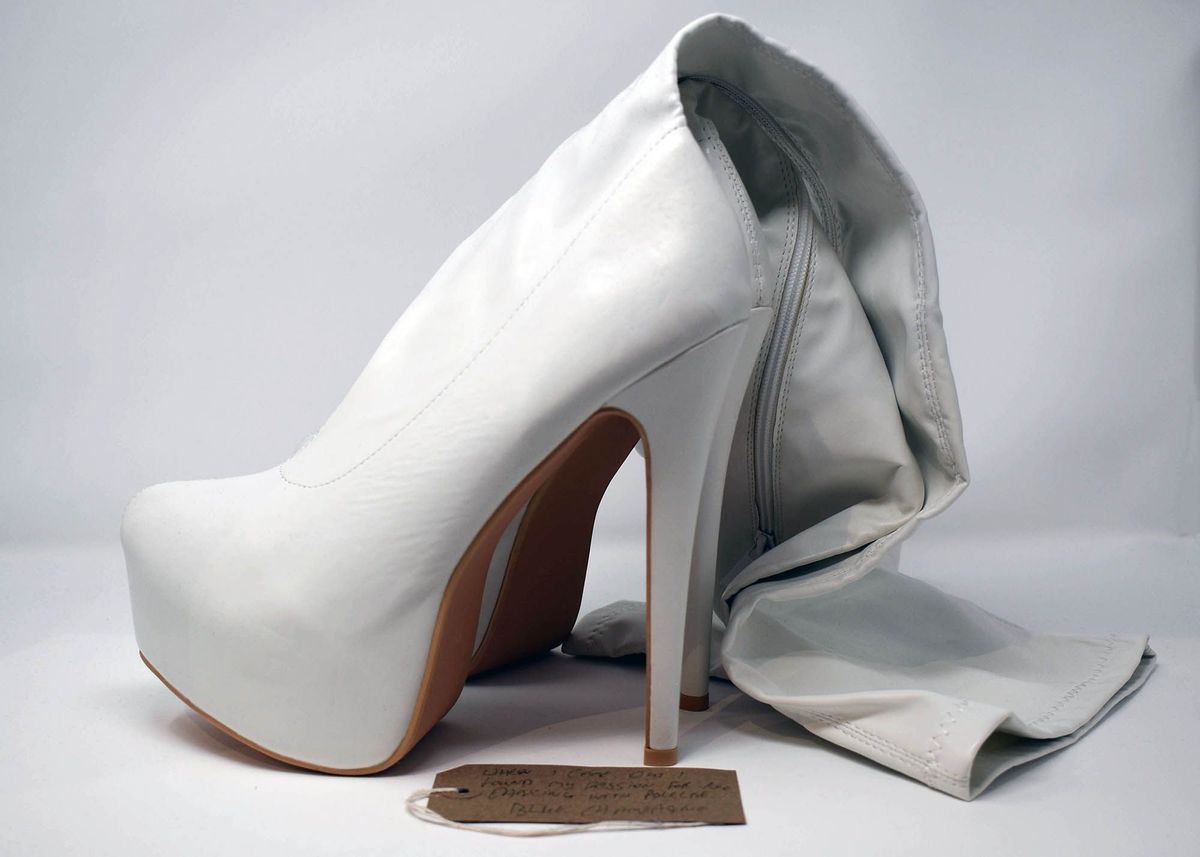 Pair of white, knee-high, high-healed boots with a brown luggage tag