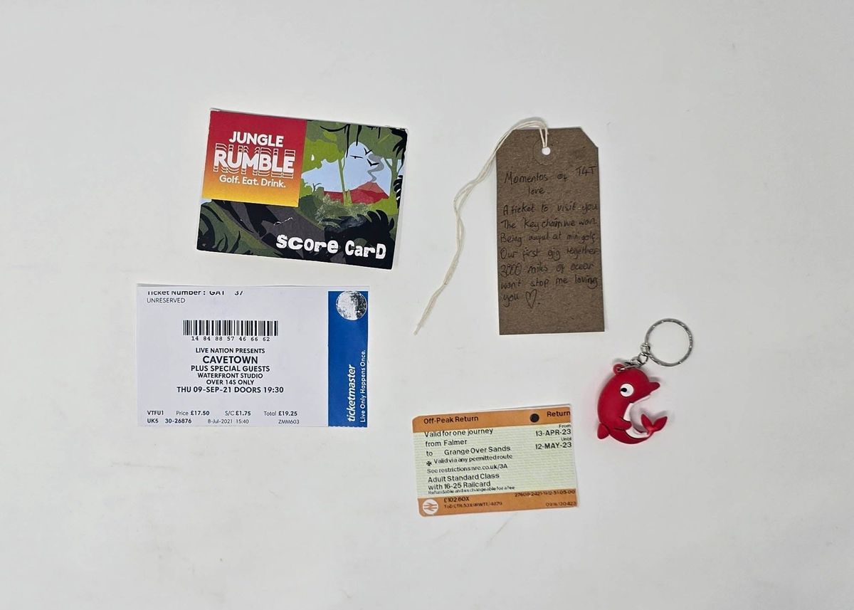 A score card for golf, a gig ticket, for Cavetown, a train ticket, a red dolphin keyring and a brown luggage tag.