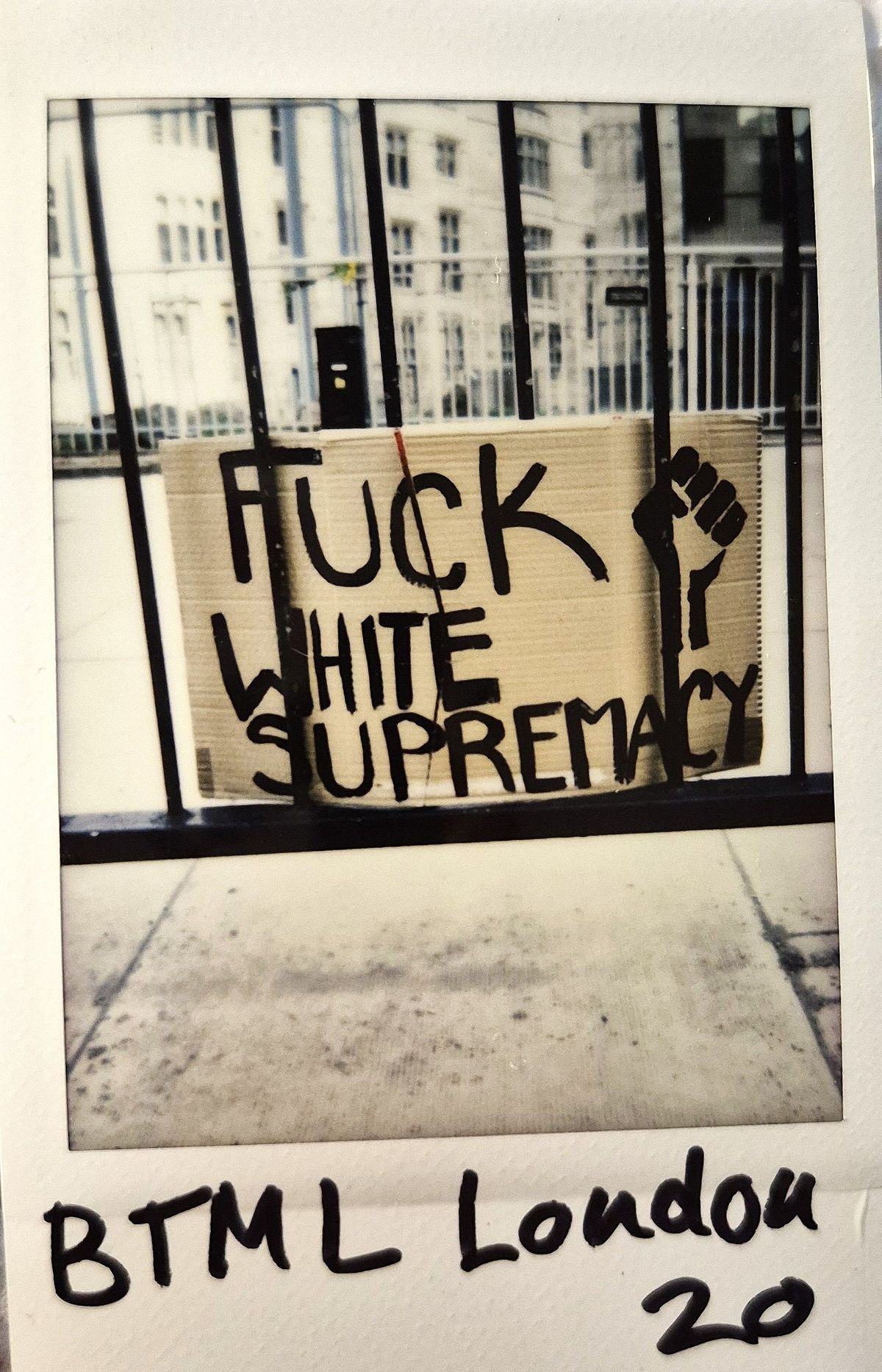 A cardboard sign saying "F*** White Supremacy" with a clenched fist, is displayed.