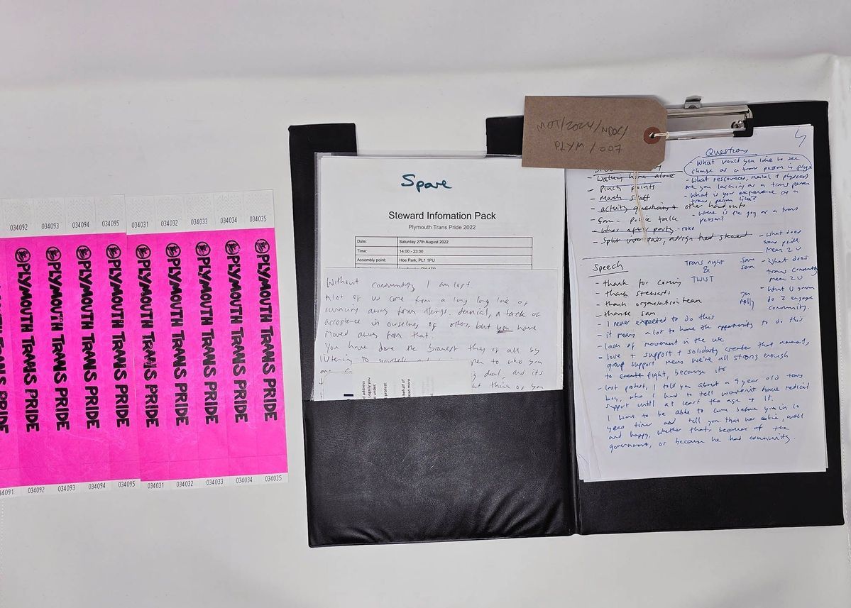 The image displays a steward information pack for Plymouth Trans Pride event, including wristbands and handwritten notes.