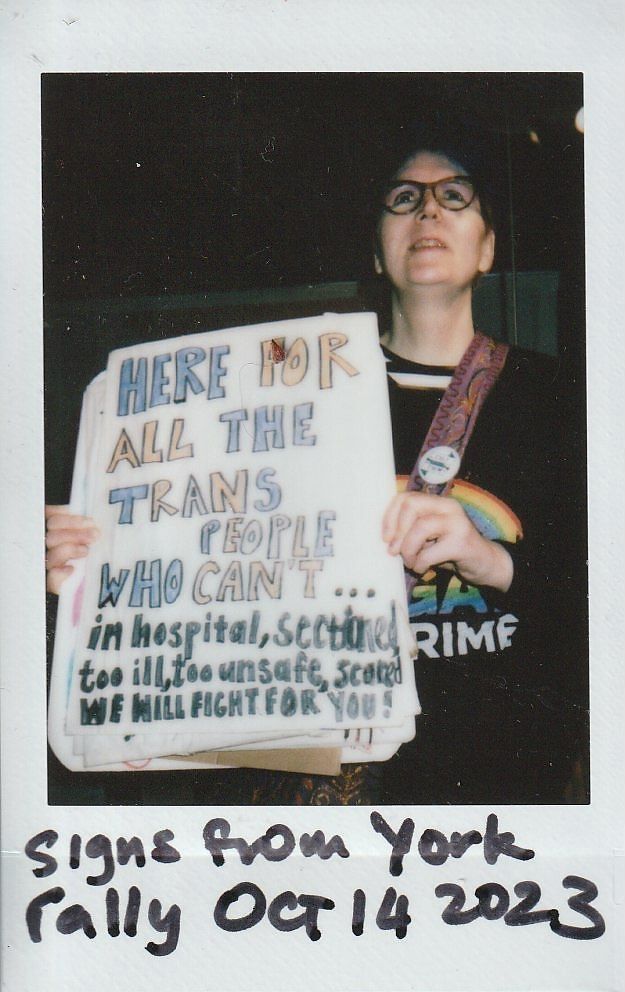 A person holds a sign supporting trans individuals during a rally in York on October 14, 202