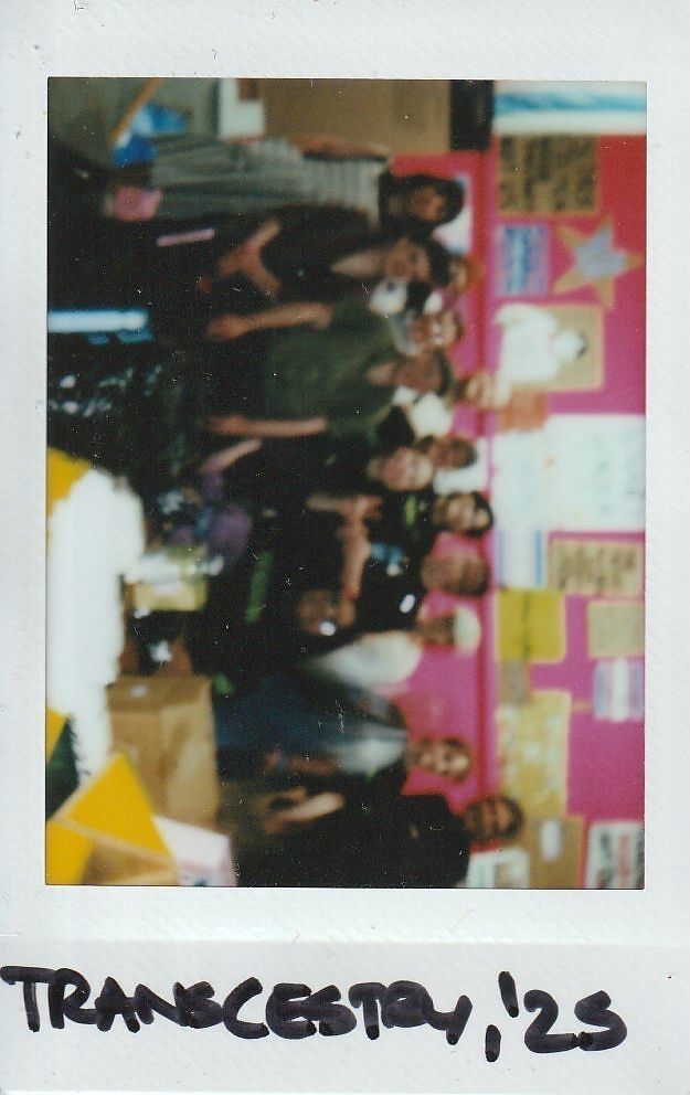 A group of people poses together in a colorful room with various posters on the walls.