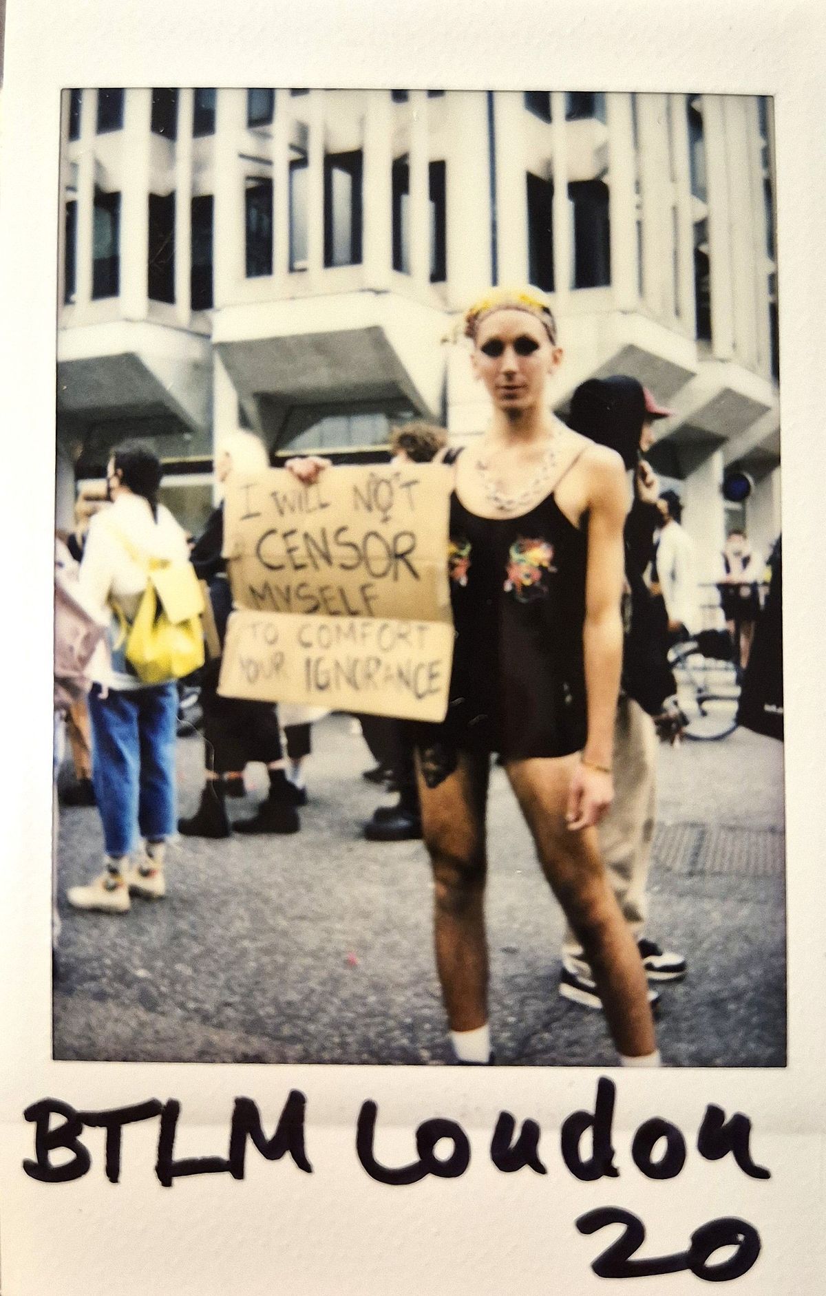 A person stands holding a sign saying, "I will not censor myself to comfort your ignorance".