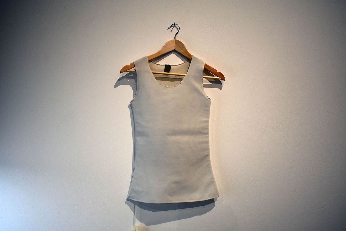 White full-length binder with black bobbles visible on the neck and shoulder seams.