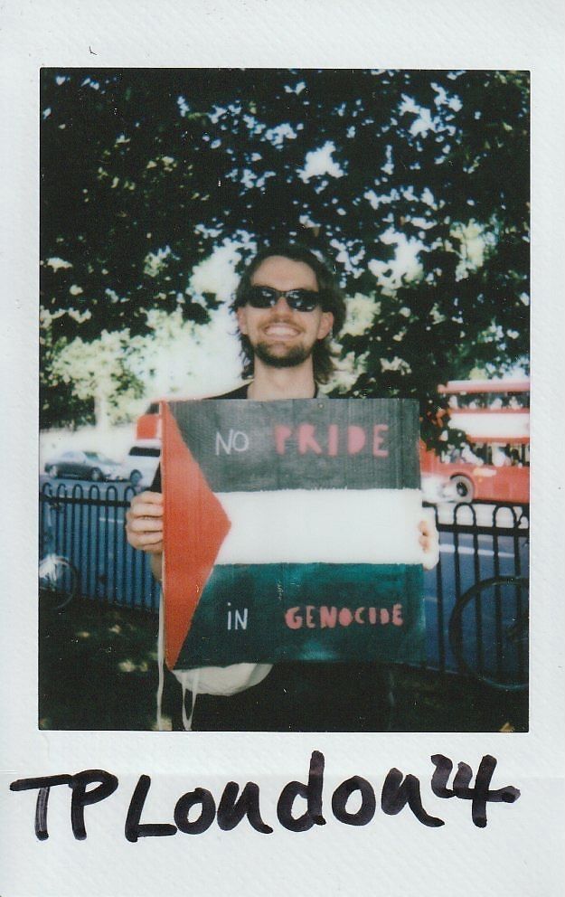 A person wearing sunglasses holds a sign reading, "No Pride in Genocide," standing outdoors.