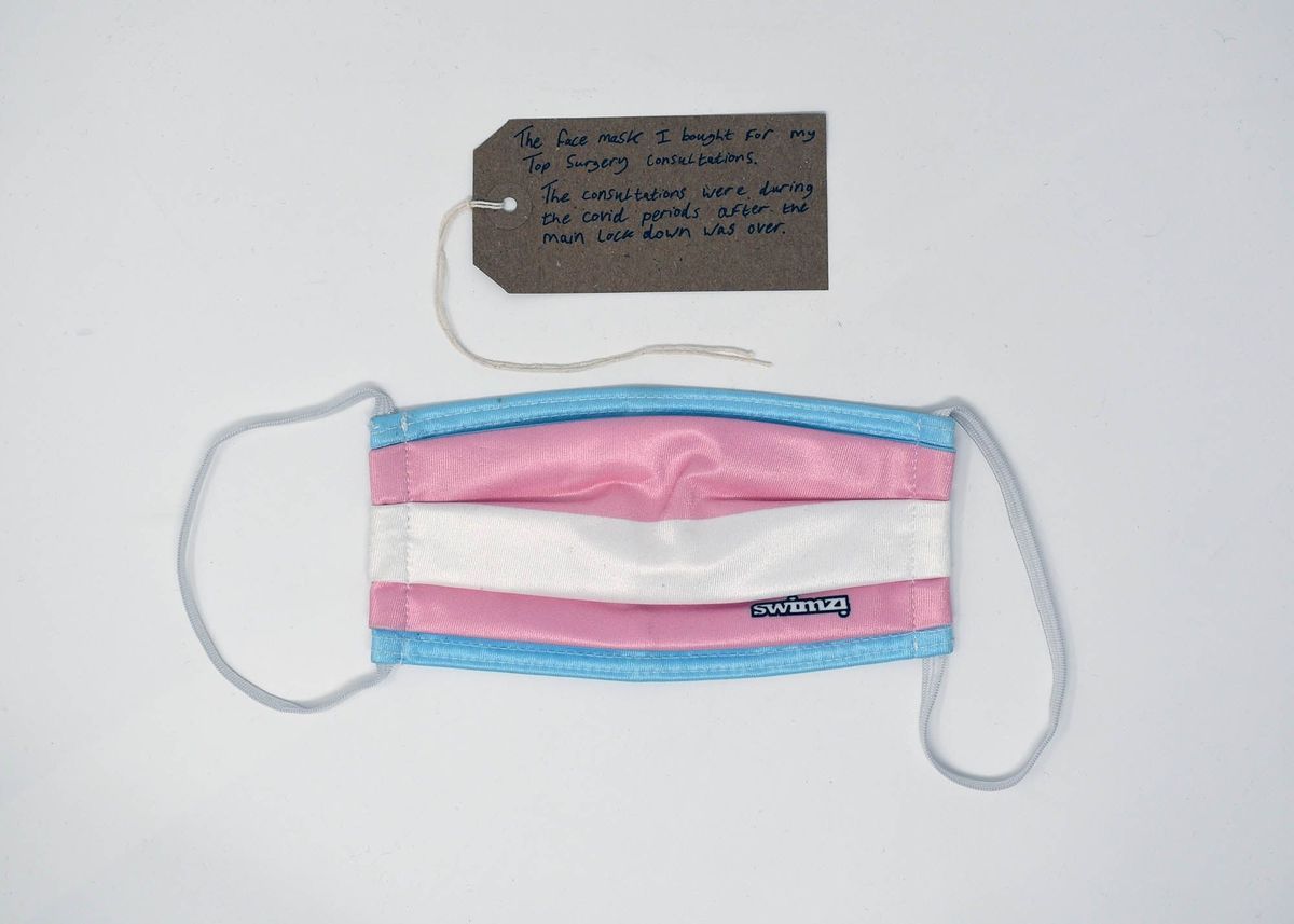 A colorful face mask lies beneath a note, possibly explaining its significance or context.