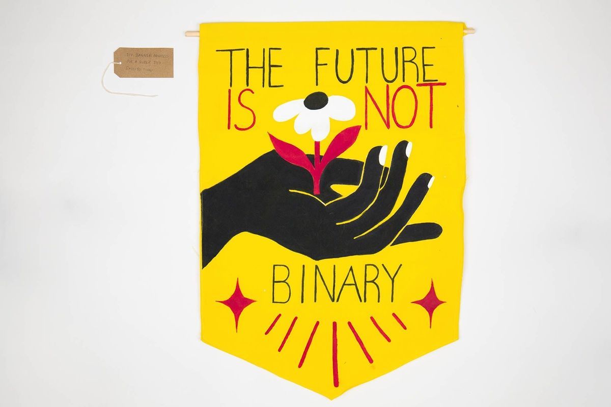 A yellow banner featuring a black hand cupping a white flower with a red stem and the text "THE FUTURE IS NOT BINARY". With a brown, handwritten luggage tag.