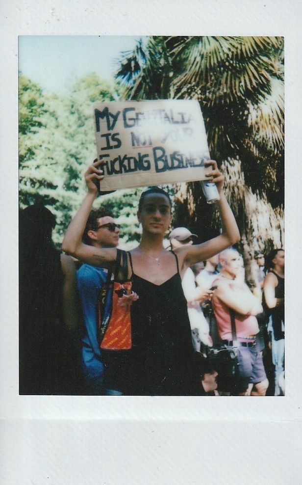 A person is holding a sign that reads, "My genitalia is not your business".