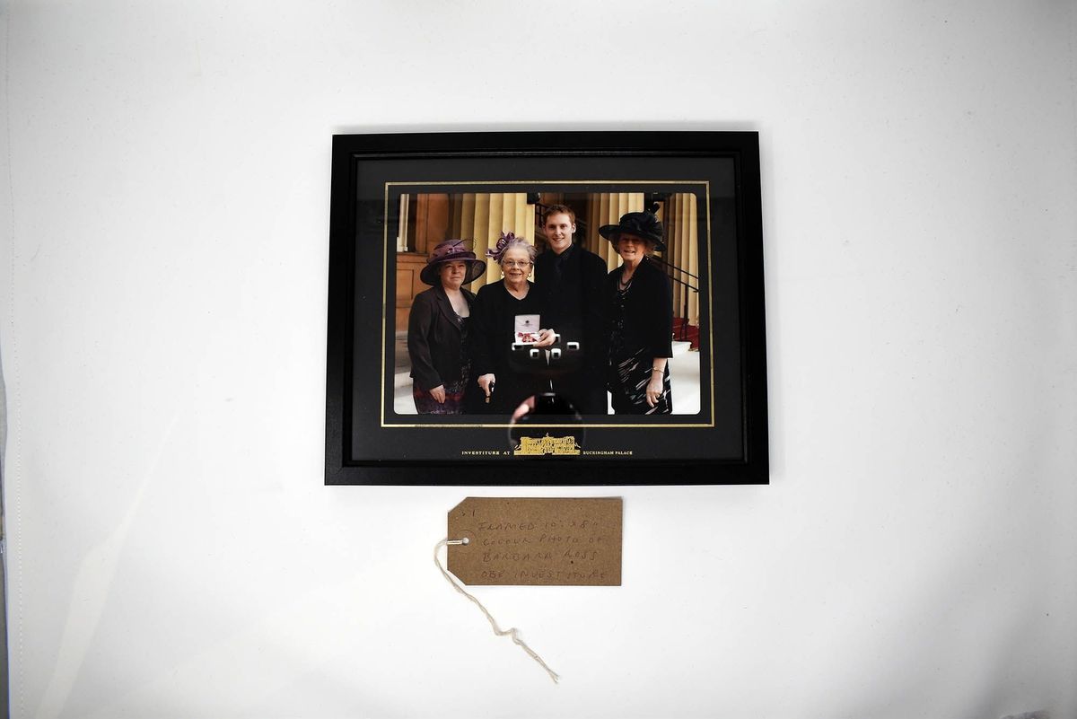 Framed photograph of four people and a brown tag.