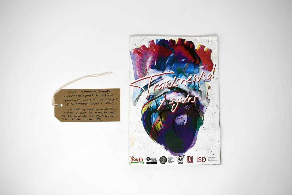 A zine with a colourful cover entitled Trawsnewid y sgwrs (Transform the conversation). With a brown handwritten luggage tag.