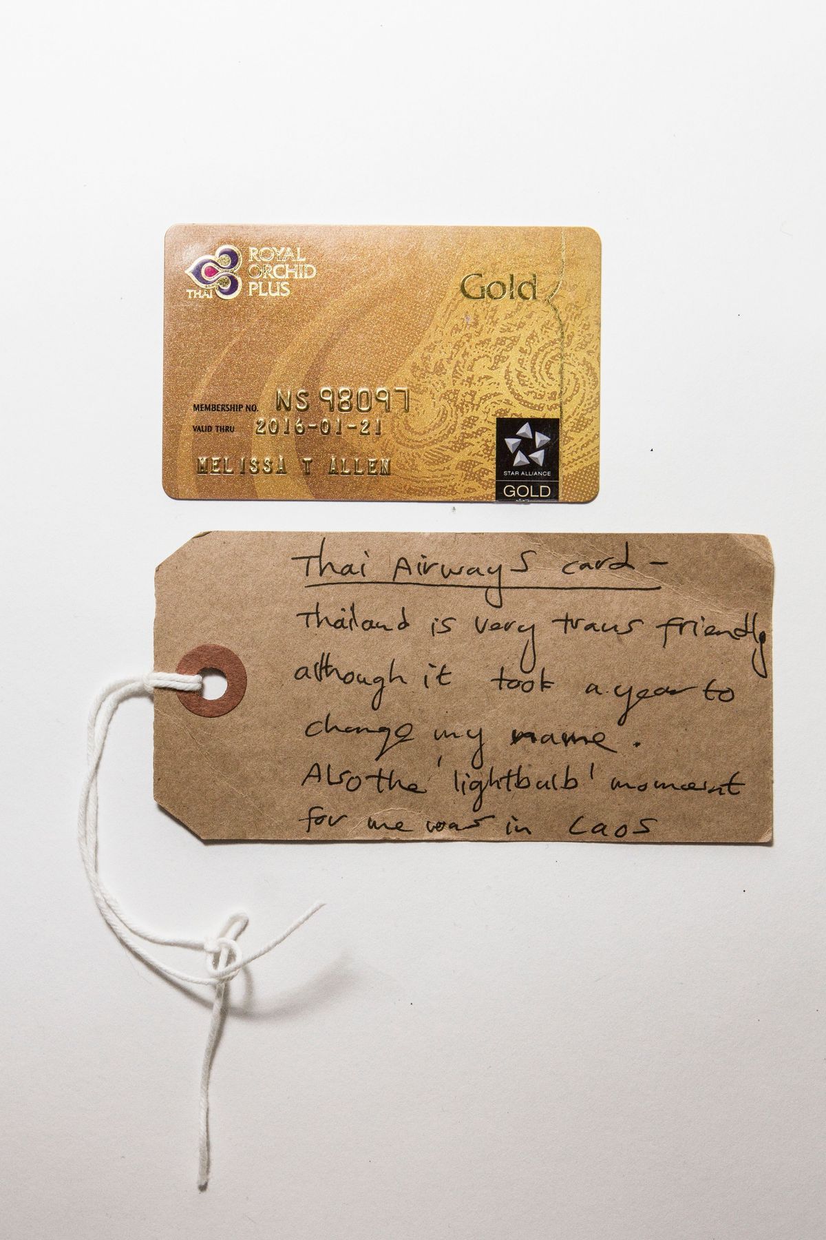 Gold coloured plastic membership card for Thai Airways & tag. Card has small scratches generally over surface, residue from sticky label on reverse and finger marks.
