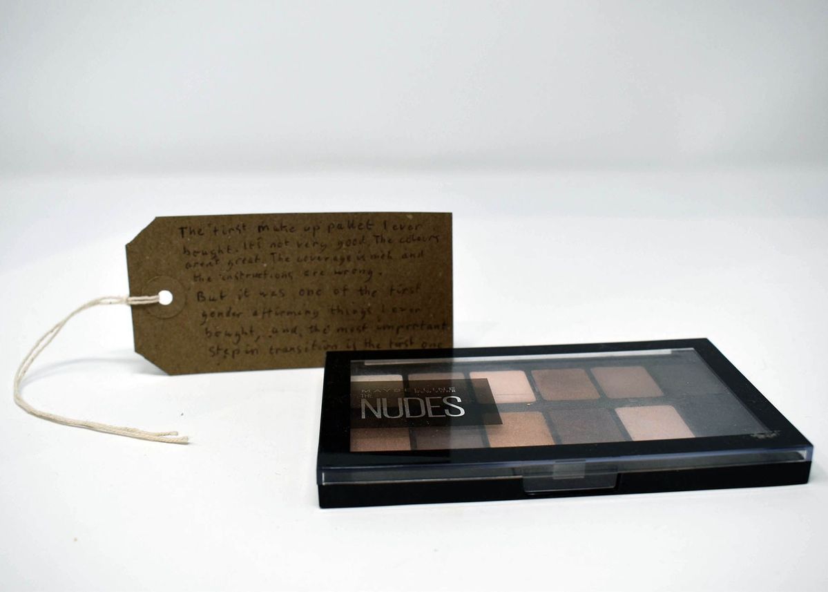 A makeup palette and a handwritten note are placed on a white surface.