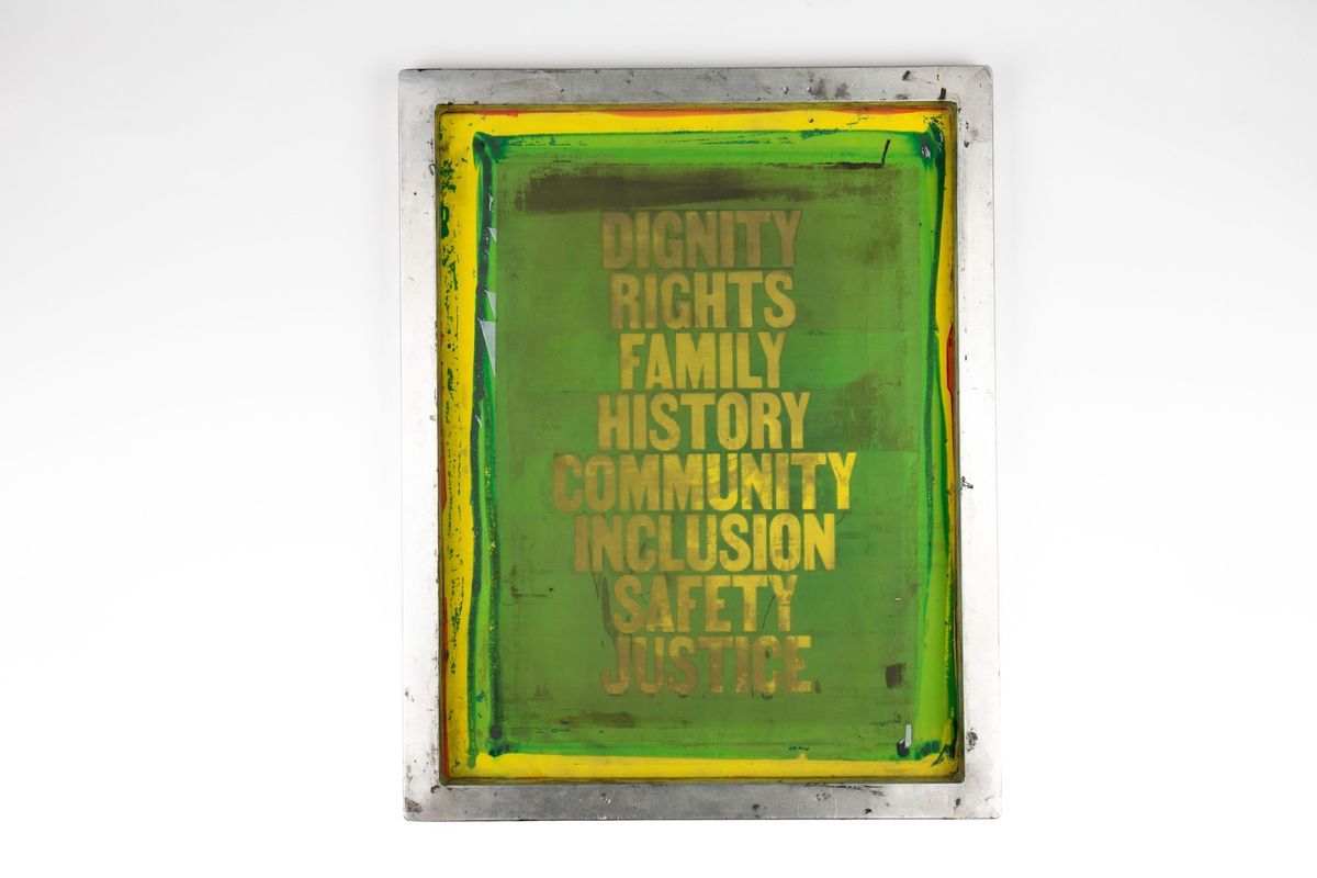 The image features a rectangular screen with 'DIGNITY RIGHTS FAMILY HISTORY COMMUNITY INCLUSION SAFETY JUSTICE'. The screen is generally green with a border of yellow and the text is yellow.
