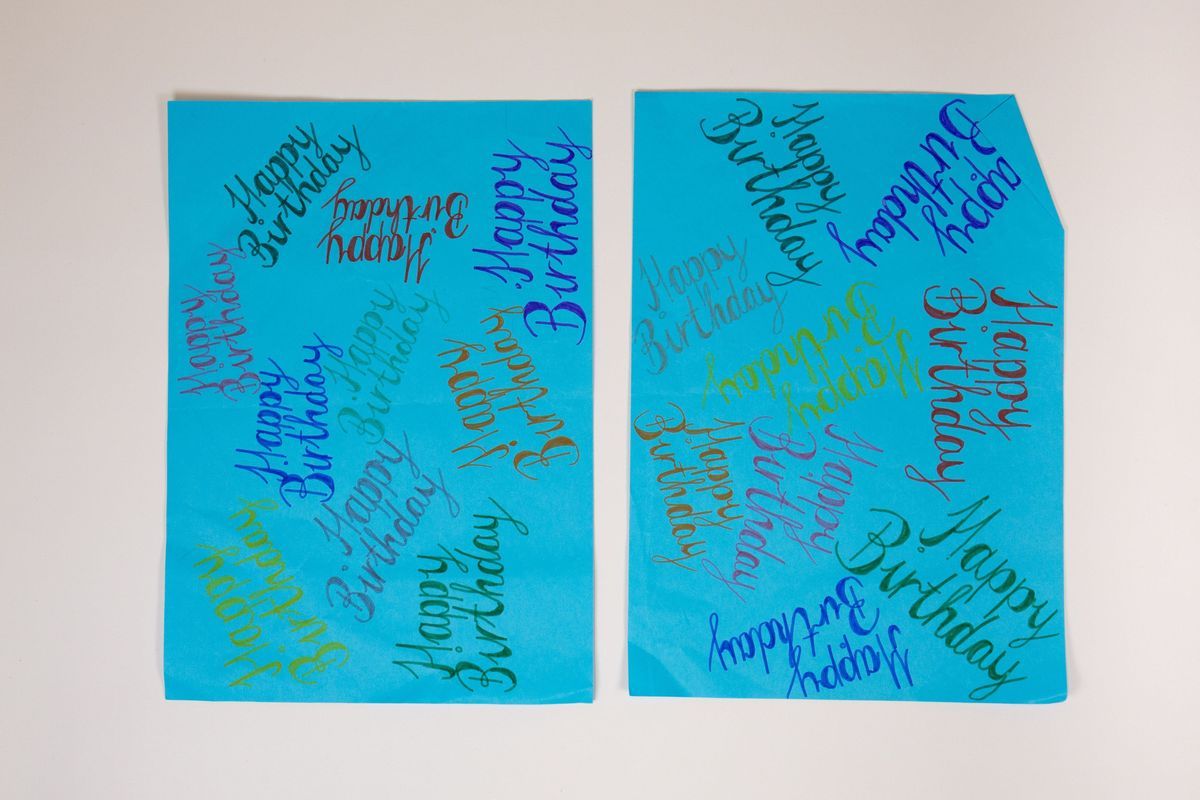 The image shows two blue sheets with "Happy Birthday" written repeatedly in various colors.