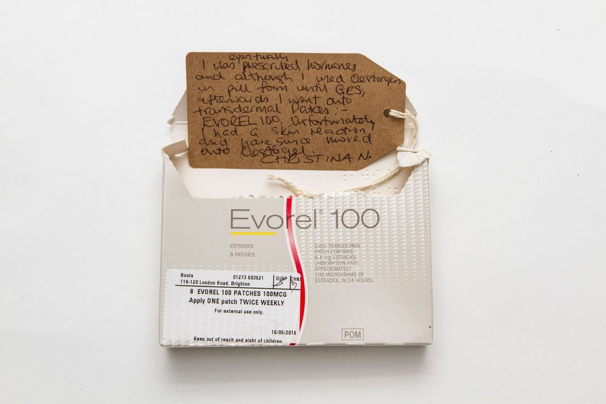 Light grey "Evorel 100" box which has been opened at the top. There is a white prescription label in the bottom left corner of the front of the box.