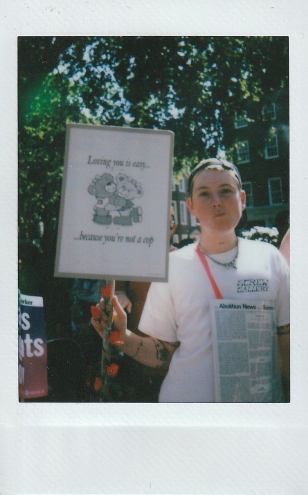 A person holds a sign reading, "Loving you is easy... because you're not a cop".