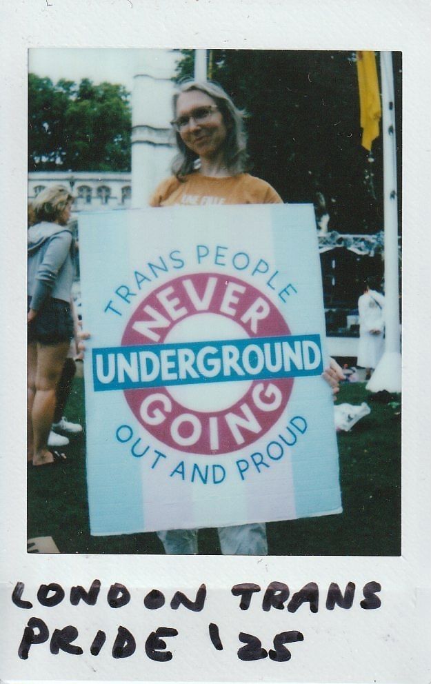 A person holds a sign that reads "Trans People Never Going Underground Out and Proud".