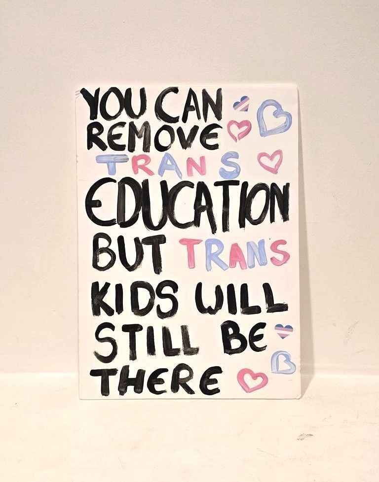 A placard which is white with black writing that says 'I'm not trapped in my body I'm trapped in other peoples perceptions of my body'.