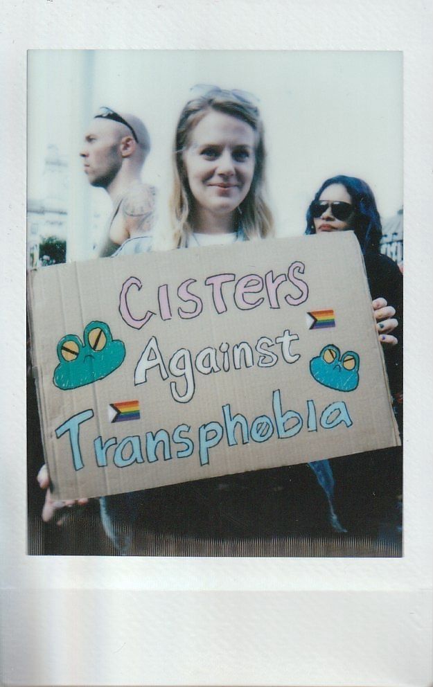 A person is holding a cardboard sign reading "Cisters Against Transphobia".