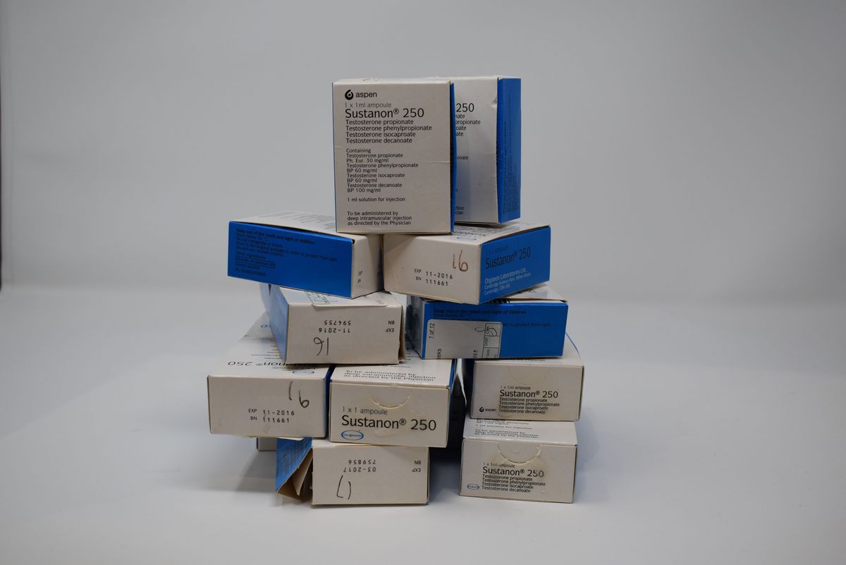A stack of boxes labeled "Sustanon 250" is arranged, featuring blue and white packaging.