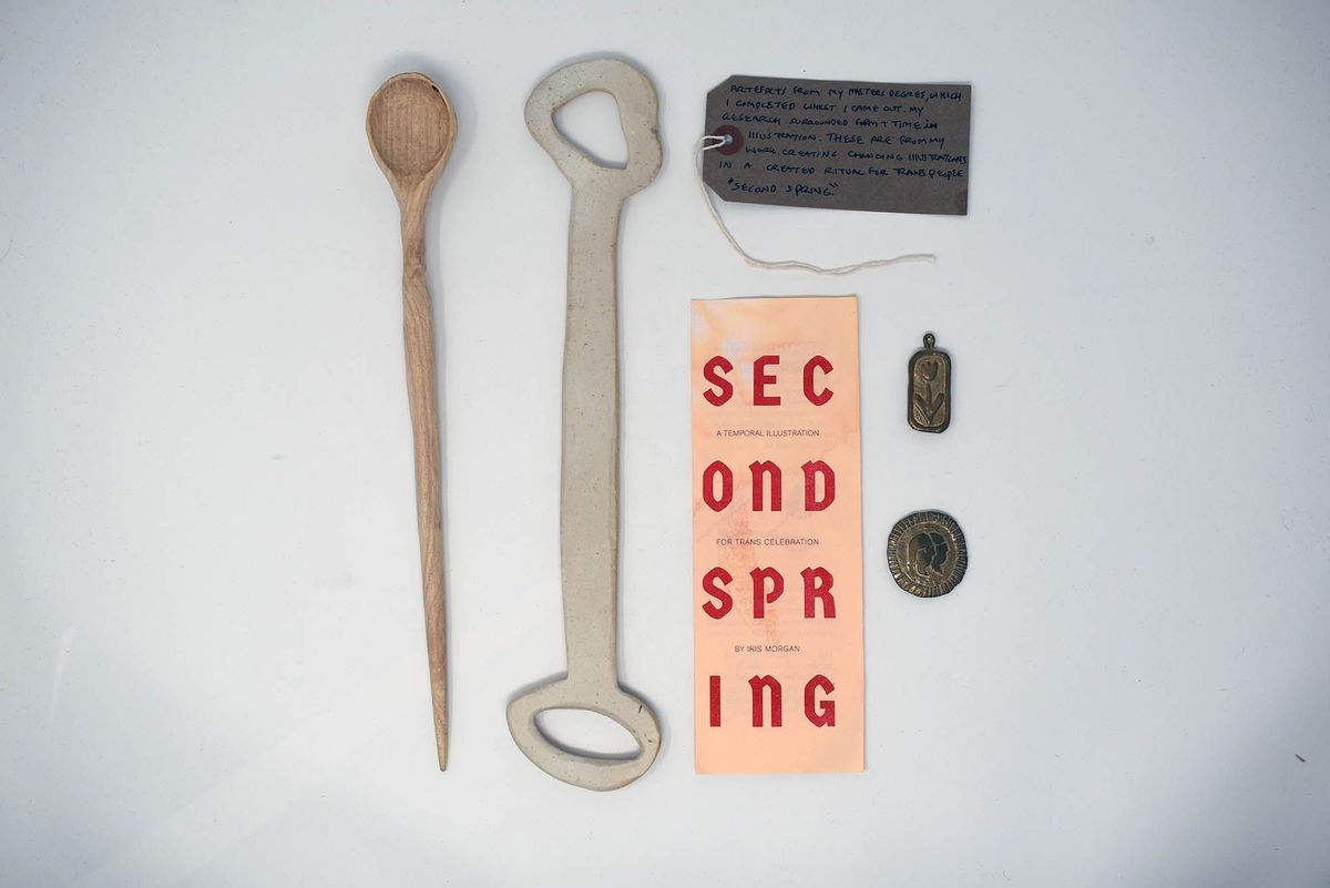The image features a wooden spoon, bottle opener, note, pamphlet, and two small medals.