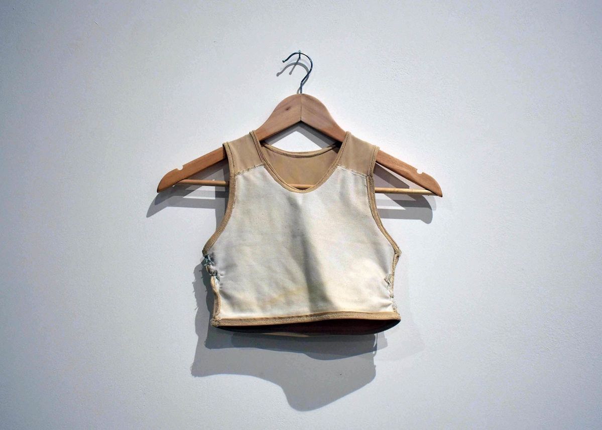 A beige binder on a wooden clothes hanger.