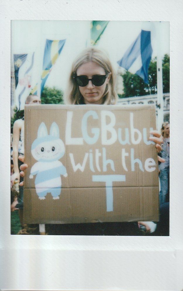 A person holds a sign which says "LGBUBU With The T".