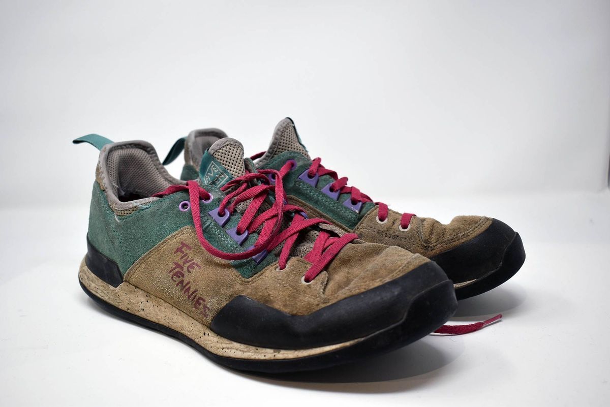 A pair of Five Ten climbing shoes. The uppers are green and brown suede and they have red laces.