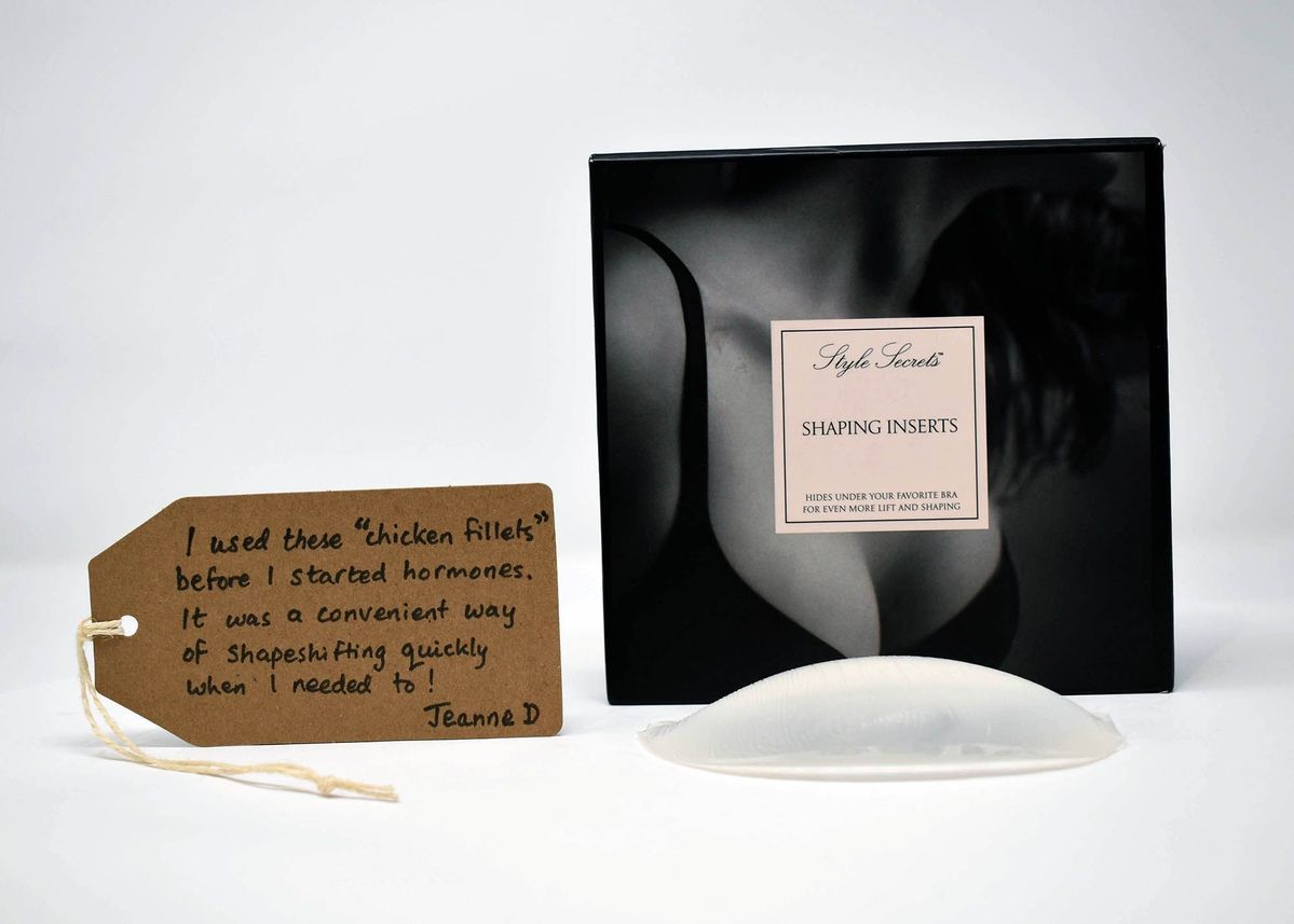 Front of a black box reading "Style Secrets Shaping Inserts. Hides under your favourite bra for even more lift and shaping" lying next to one silicone breast inserts and a brown tag with writing on it.
