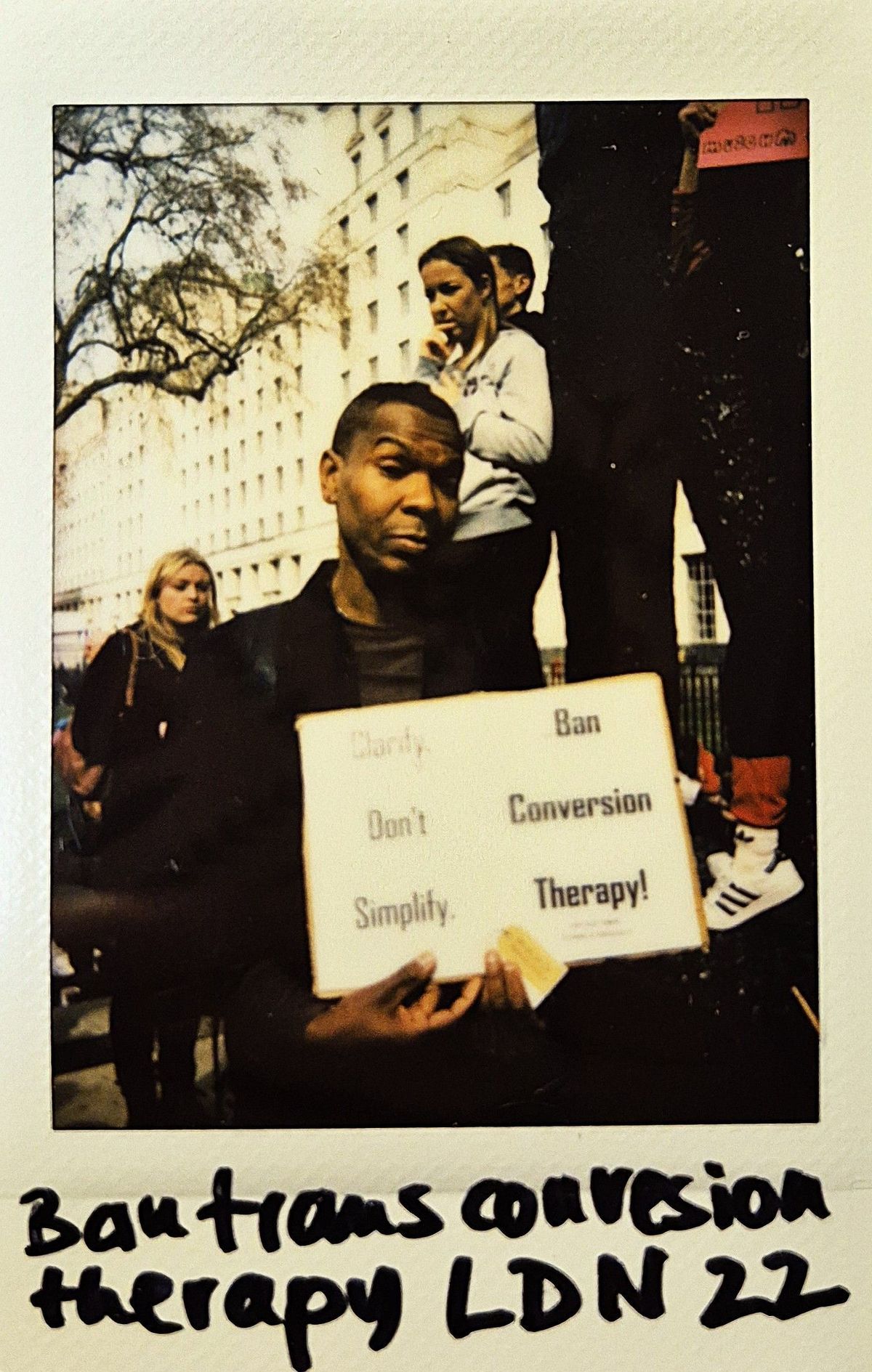 A person holds a sign that reads "Ban Conversion Therapy!" during a protest event.