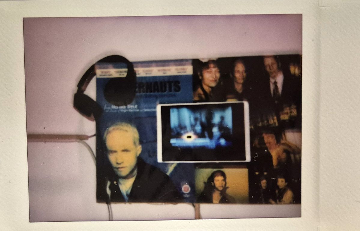 A small display features headphones, posters, photographs, and a tablet with a blurred screen.