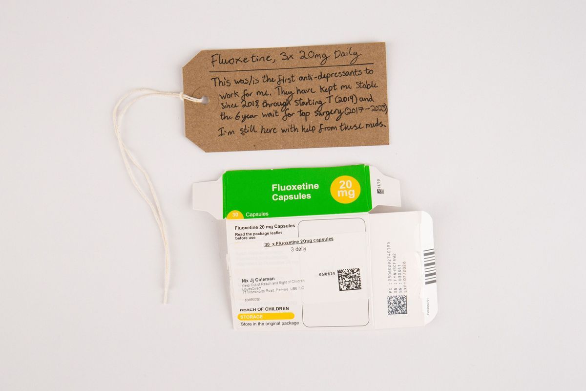An green and white empty box for Fluoxetine 20mg. With a brown, handwritten luggage tag.