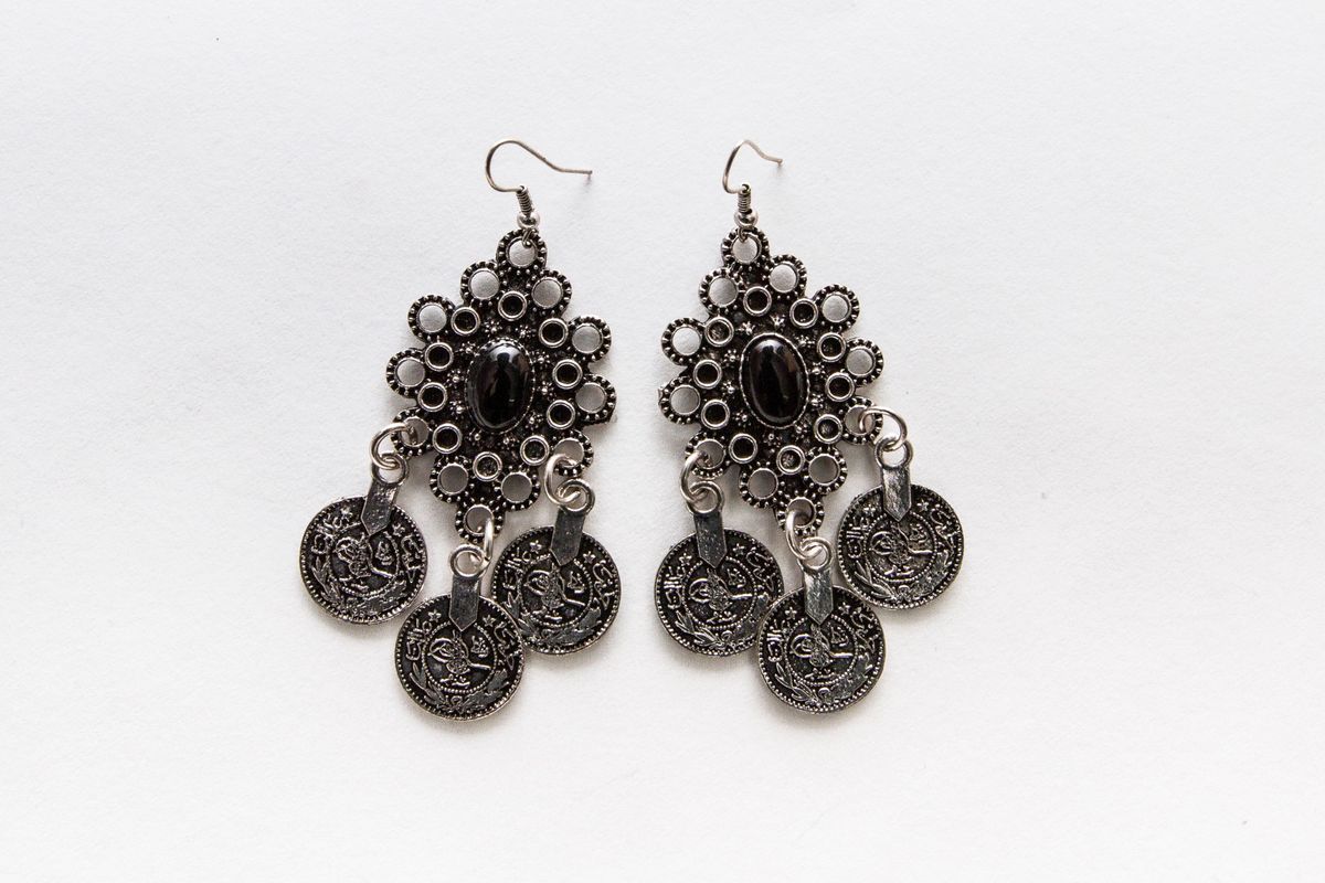 One pair of earrrings in drop style with hook, metal filigree, each with central black bead and three small discs hanging.