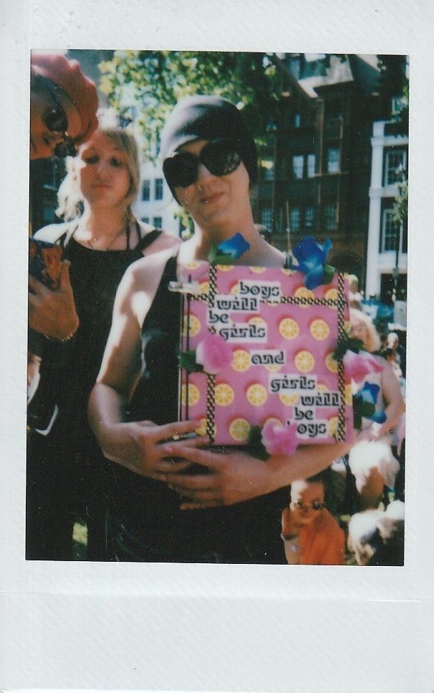 A person holding a colorful sign which says "boys will be girls and girls will be boys".