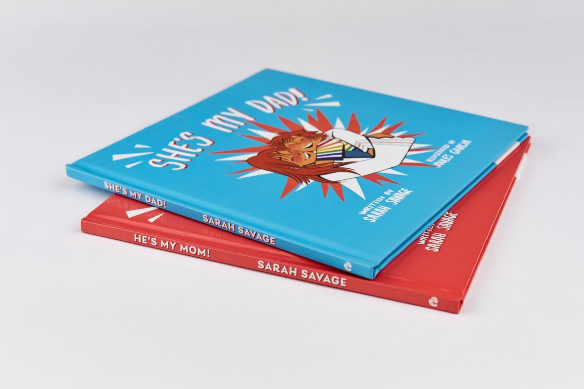 Two Children's Books - 'She's My Dad!' and 'He's My Mom!' which are blue and red and stacked on top of each other.