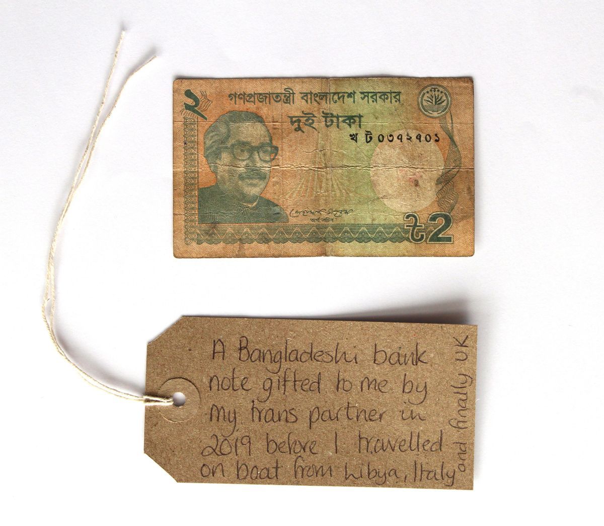 A Bangladeshi bank note with a brown luggage tag.
