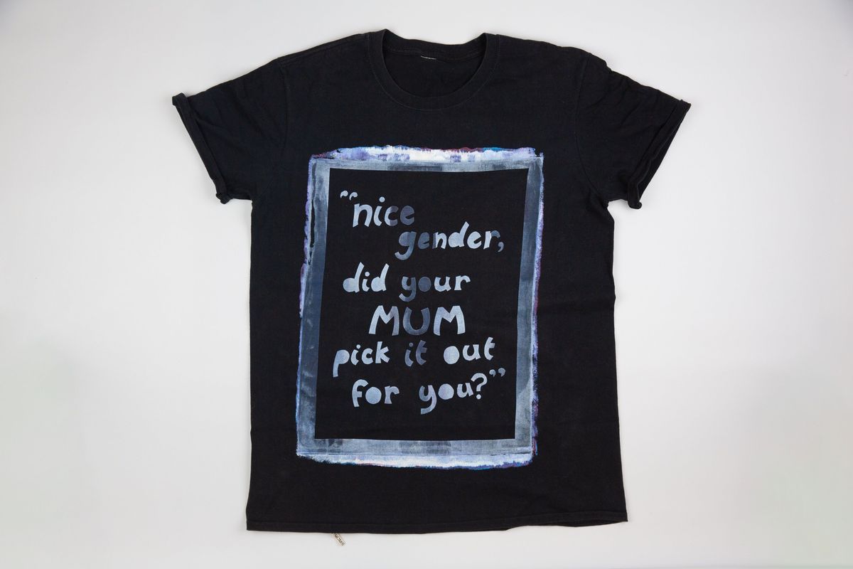 The black T-shirt has a printed quote framed with colorful paint, which says 'Nice Gender Did Your Mum Pick It Out For You?'
