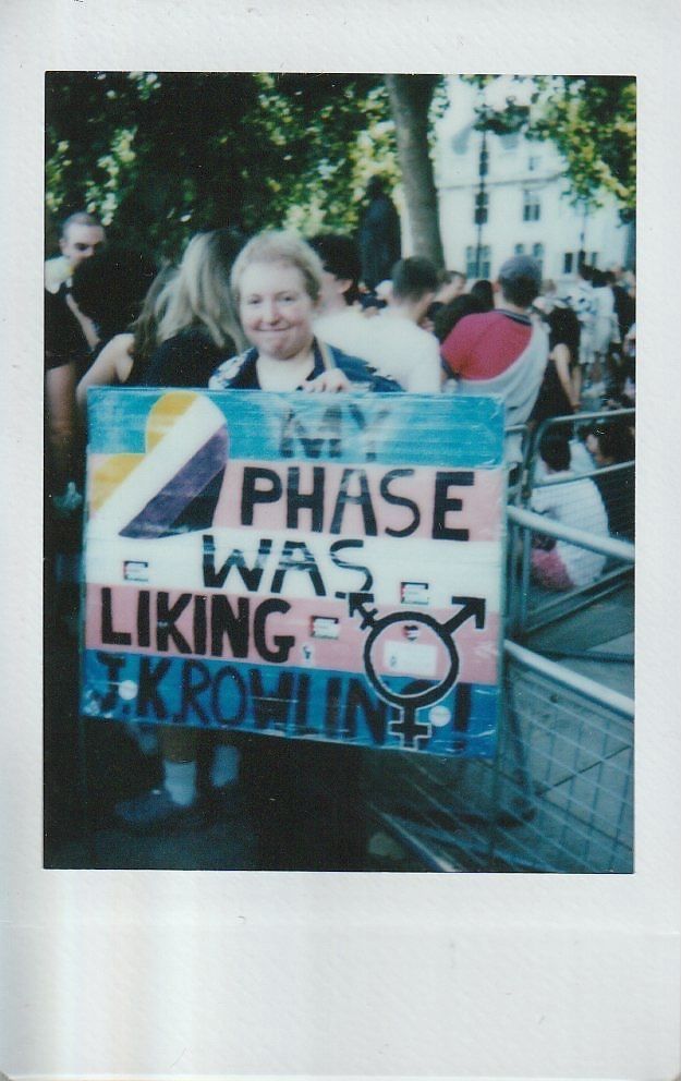 A person is holding a colourful protest saying "My Phase Was Liking J K Rowling".