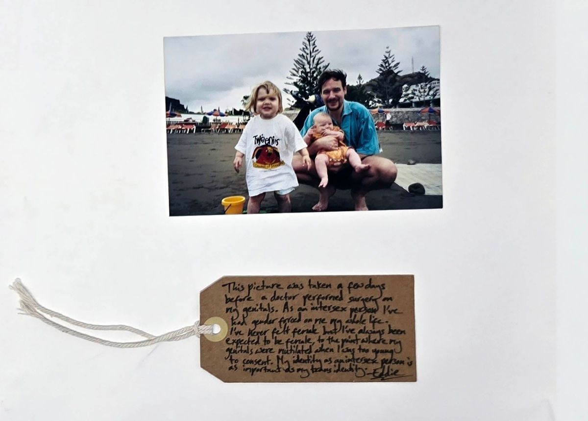 Colour photograph; group picture taken outdoors of adult male holding baby with a toddler in Tweenies T shirt.